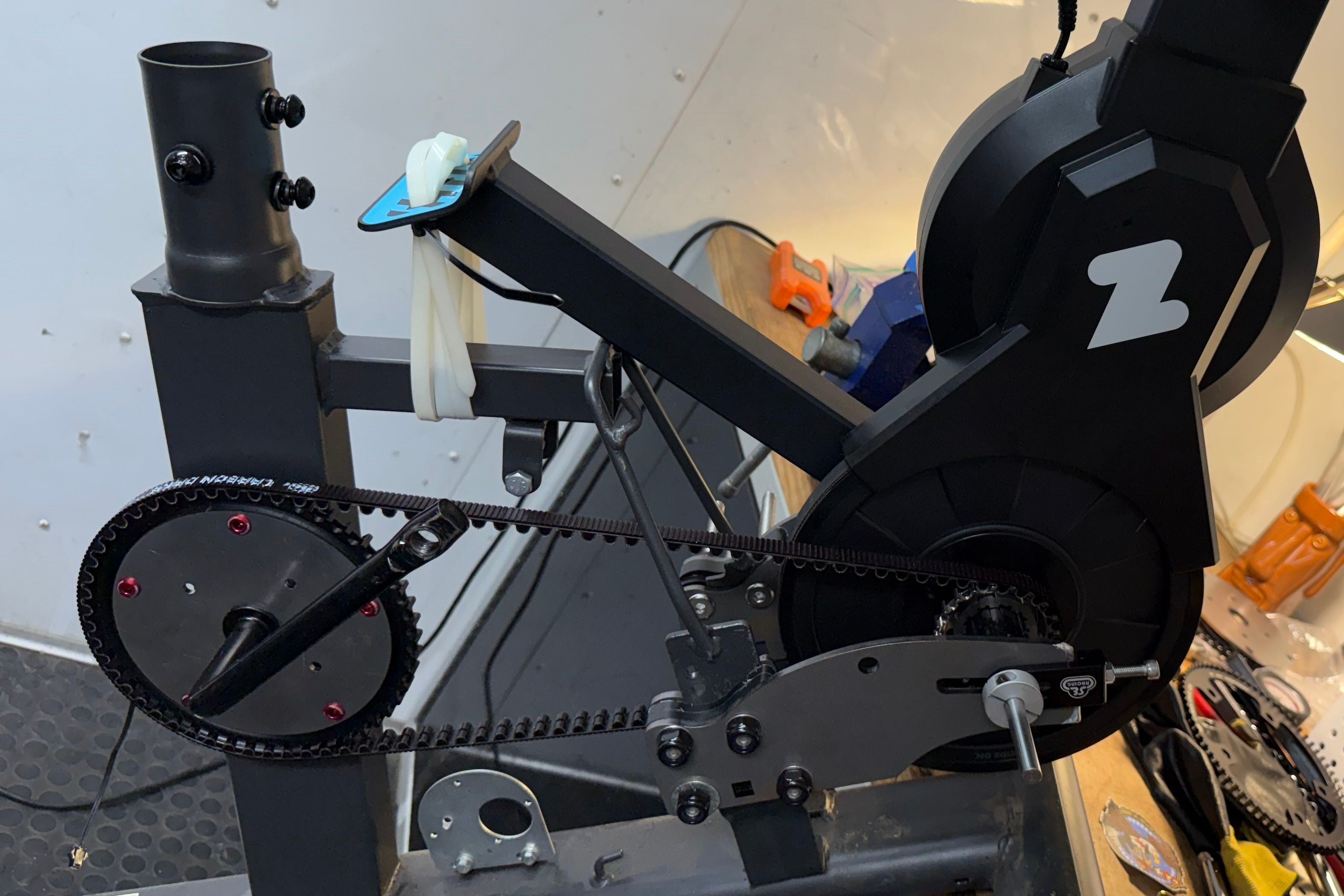 Side view of a Schwinn recumbent frame with a large front pulley and black toothed belt