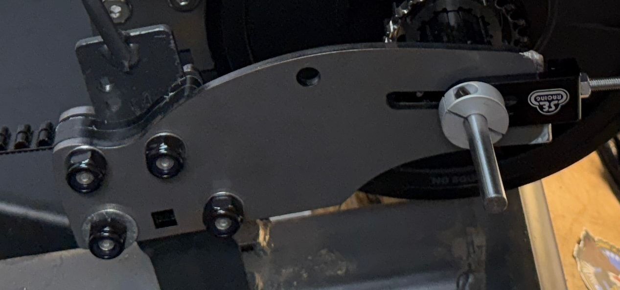 Black purpose-built steel mount secured to a gray Schwinn recumbent frame with four bolts