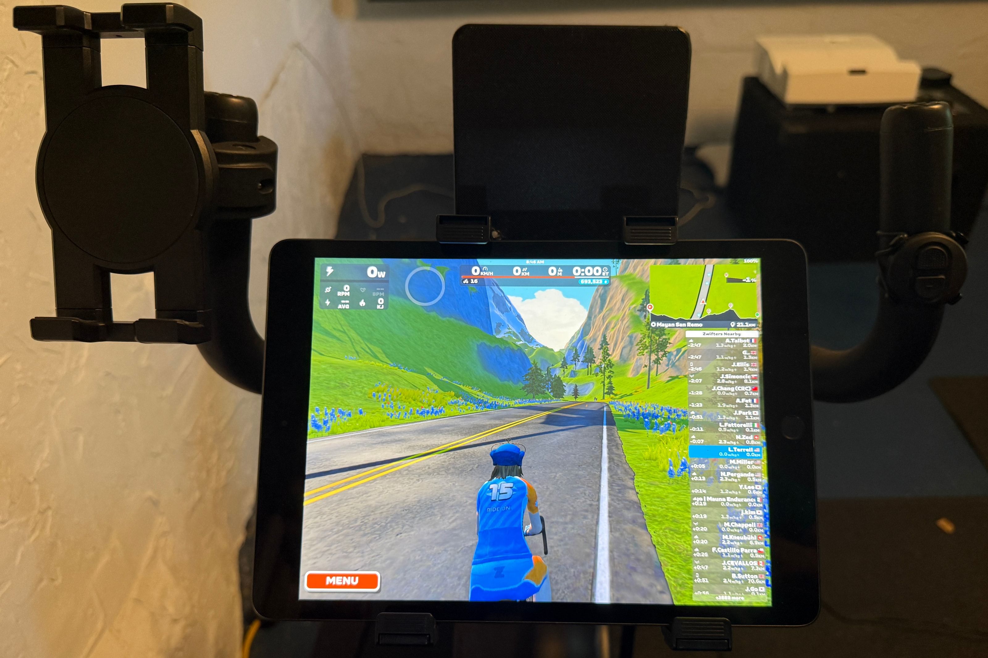 Tablet showing a virtual cycling scene between recumbent handlebars with small control mounts